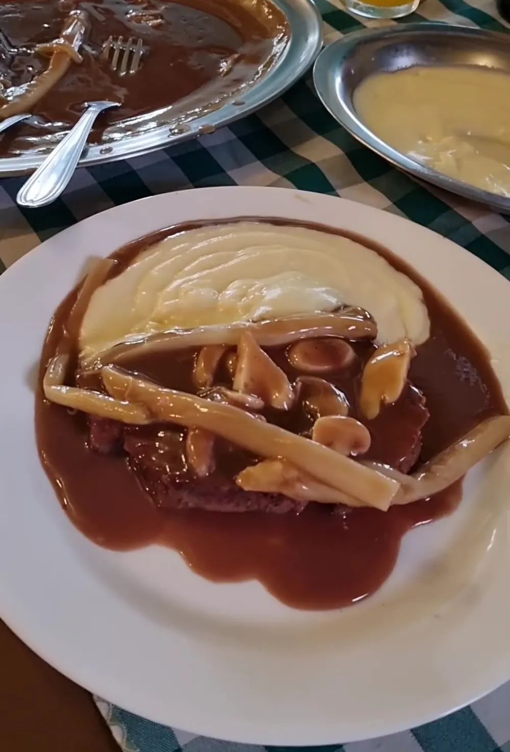 Prato da casa com molho escuro, cogumelos e batata palha